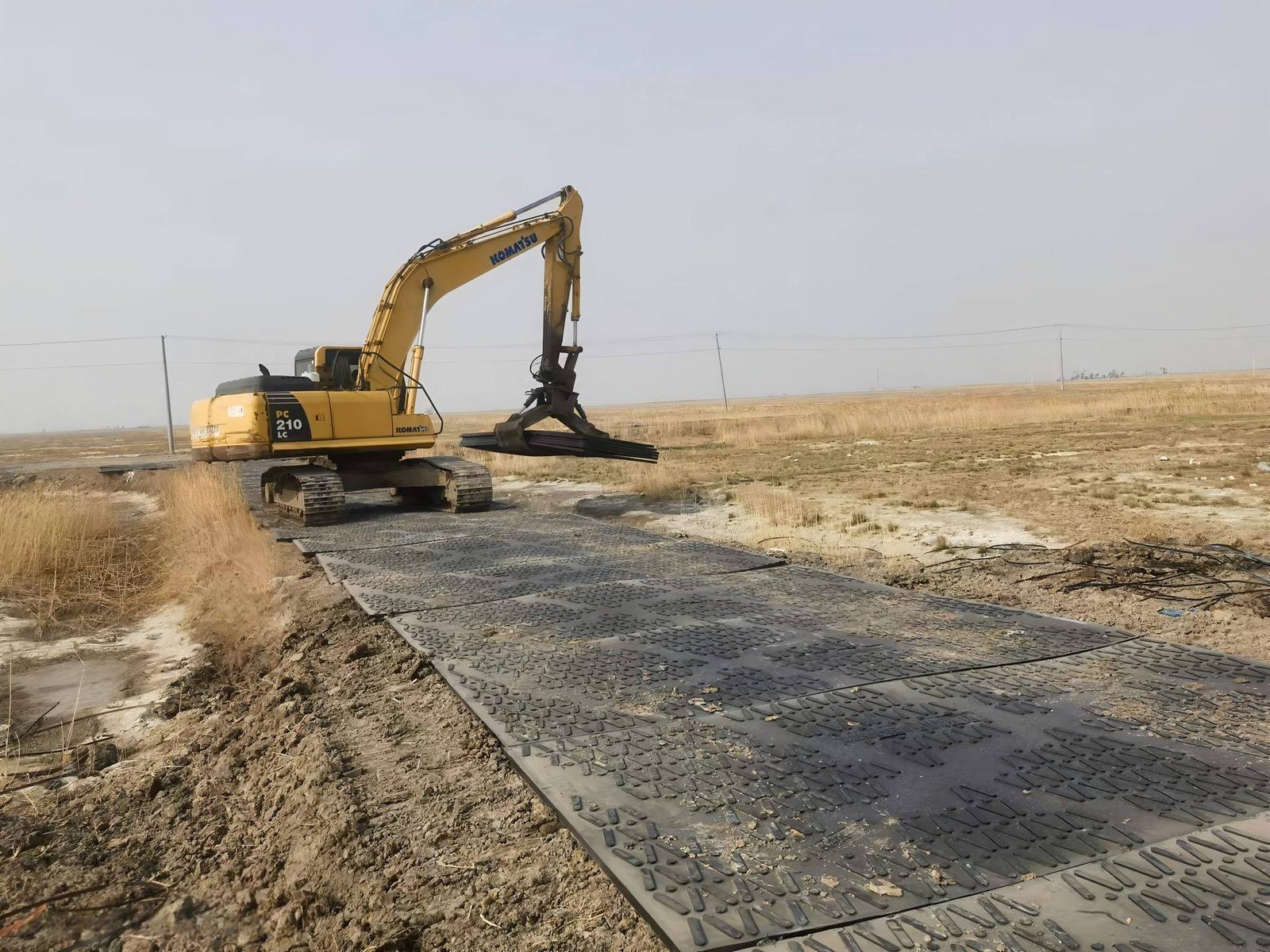 Excavator operating on ground protection mats