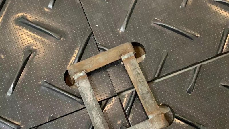 Steel connector locking two HDPE ground protection mats together through their edge holes